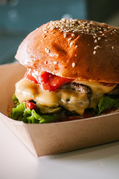 Freshly prepared cheeseburger in a paper box is ready to eat Food delivery concept