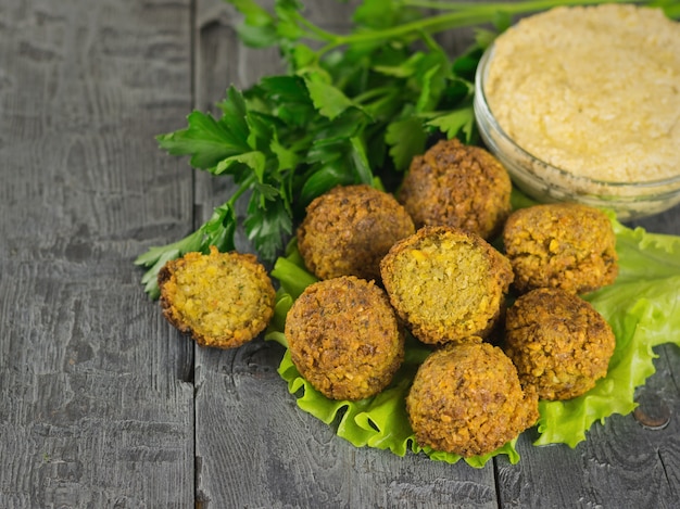 Foto falafel appena preparato con pasta di tahini e olio d'oliva sul tavolo rustico in legno scuro