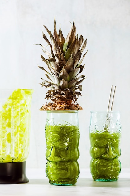 Freshly prepared green pineapple smoothie in glasses with faces. Healthy morning breakfast concept.