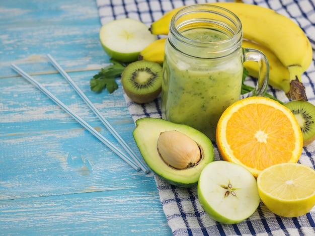 Un frullato appena preparato di avocado, banana, arancia, limone e kiwi su un tavolo di legno blu. dieta cibo vegetariano. cibi crudi.