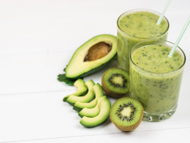 A freshly prepared smoothie of avocado, parsley, lemon and kiwi on a white table diet vegetarian food