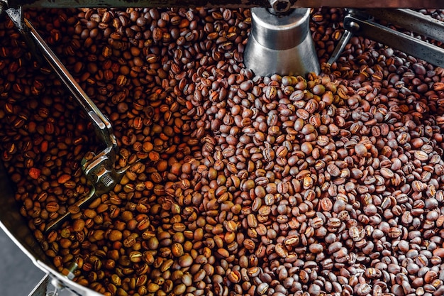 Freshly roasted aromatic coffee beans over a modern coffee roasting machine