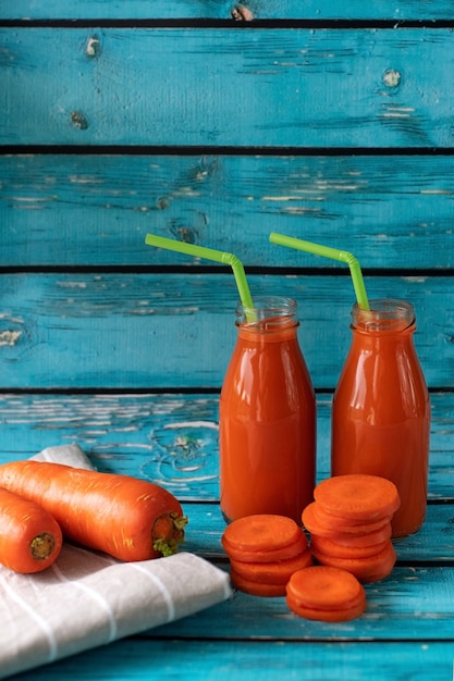 Succo di carota appena spremuto su uno sfondo blu brillante