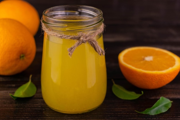 Freshly squeezed orange juice in a jar on a dark wooden background