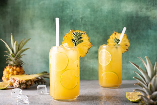 Freshly squeezed pineapple juice with lime wedges and ice in glass jars