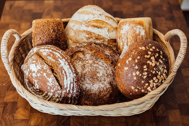 Freshly and warm baked bread rolls in the basket on wooden table. Made by artisan.