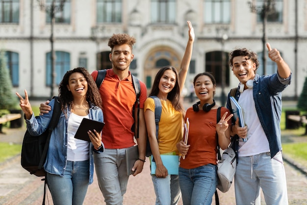 Freshmen orientation group of first year students with workbooks posing together outdoors