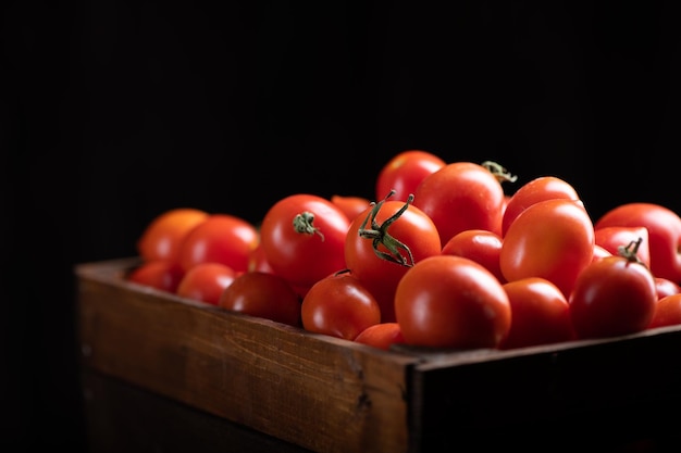 Scatola di pomodori rossi freschi sulla tavola di legno