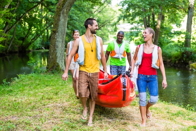 Freunde tragen zusammen Kajak zum Wald Fluss
