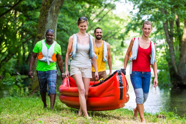 Freunde tragen zusammen kajak zum wald fluss