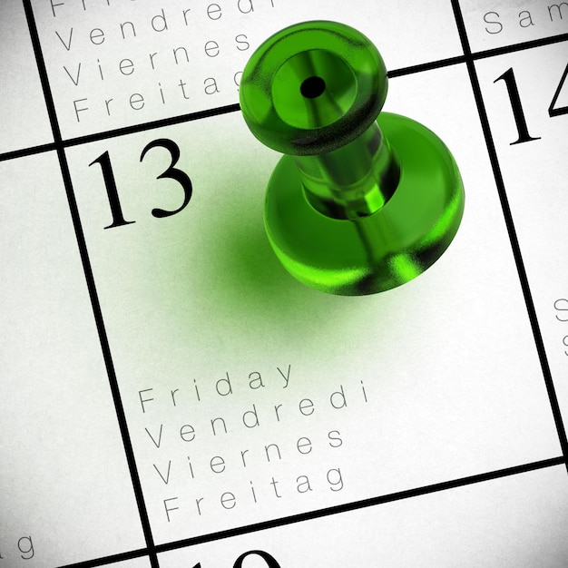 Friday the 13th written onto a multilingual calendar with a red thumbtack with transparency