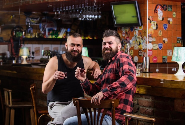 Friday relax in pub Friends relaxing in pub Cheers concept Hipster brutal bearded man drinking alcohol with friend at bar counter Men drunk relaxing at pub having fun Strong alcohol drinks