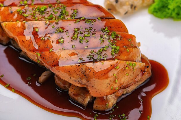 Фото Жареное и нарезанное мясное филе с соусом на белой тарелке