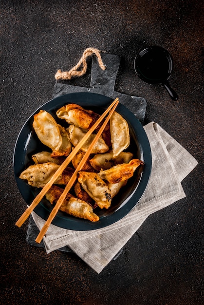 Fried asian dumplings Gyoza  on dark plate served with chopsticks and soy sauce