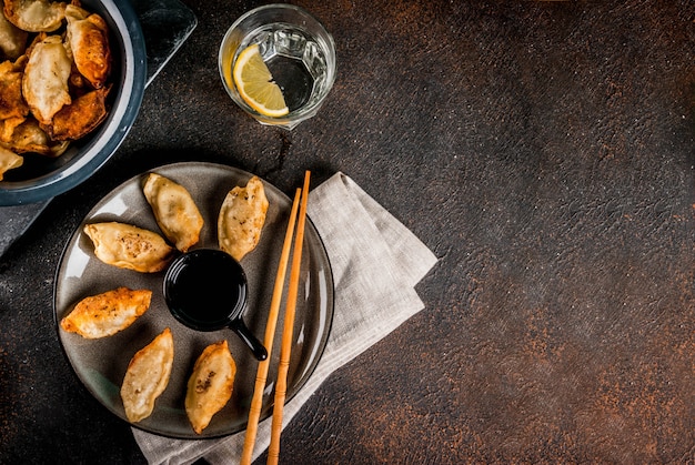 Fried asian dumplings Gyoza  on dark plate served with chopsticks and soy sauce