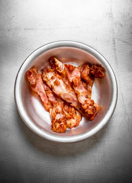 Fried bacon in a bowl. on the Metal table.