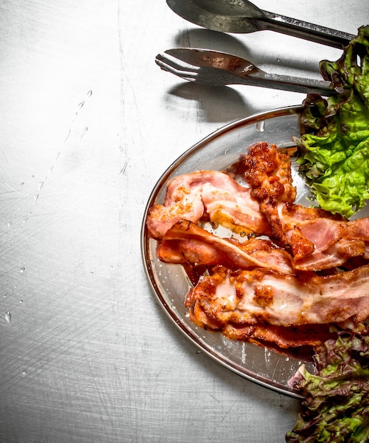 Fried bacon with greens on the Metal table