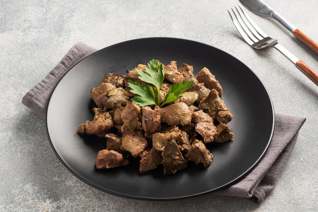 Photo fried or baked chicken liver with onion and sauce green parsley leaves on a plate meat dish enriched with iron