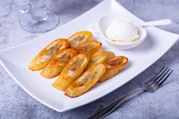 Fried bananas with honey, cinnamon, coffee and ice cream. Close-up.