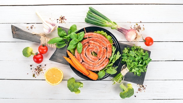 Fried barbecue sausages with fresh vegetables On a wooden background Top view Copy space