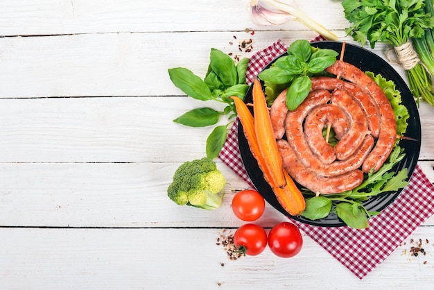 Fried barbecue sausages with fresh vegetables On a wooden background Top view Copy space