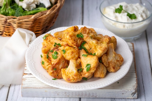 Fried in batter Cauliflower florets served on a black plate on a grey concrete table with ingredients view from above closeup flatlay copy space Turkish name karnabahar kizartmasi