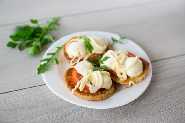 Fried in batter sandwiches with tomatoes and mozzarella in a plate with herbs