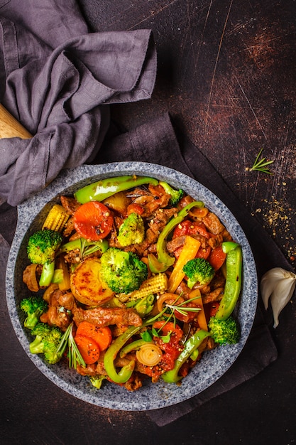 Photo fried beef stroganoff with potatoes and vegetables in a pan, top view.