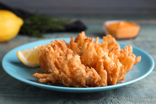 Fried blooming onion served on blue wooden table closeup