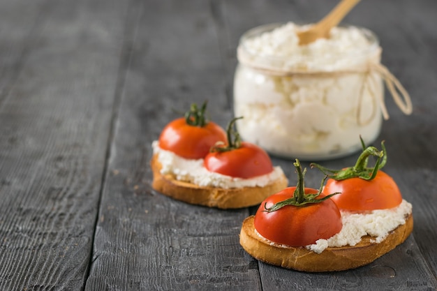 Fried bread, cottage cheese and tomato halves on wooden table.