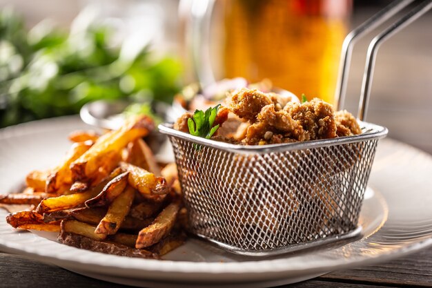 Fried breaded chicken nuggets with chips served on a plate.