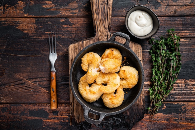 Fried Breaded Shrimps  Prawns in a pan. Dark wooden background. Top view.