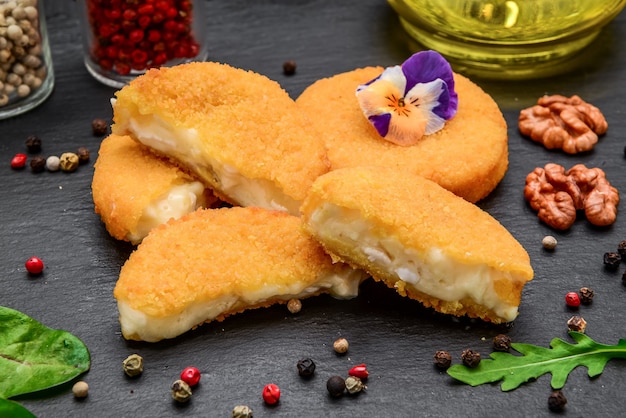 Fried brie cheese in batter on a black stone board. Camembert Cheese