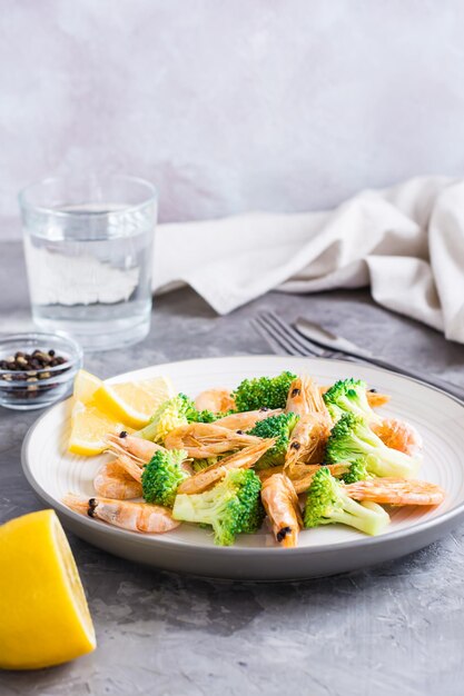 Fried broccoli and shrimp on a plate on the table healthy vegetarian food vertical view copy space