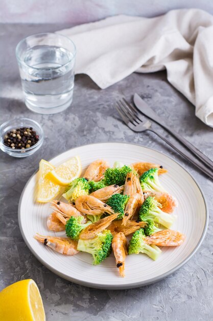 Fried broccoli and shrimp on a plate on the table Healthy vegetarian food Vertical view