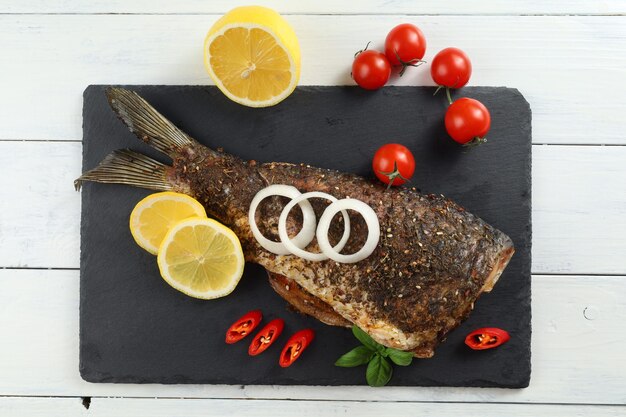 Fried carp fish on the table Baked fish with vegetables