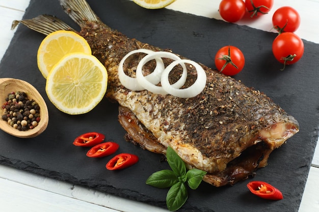 Fried carp fish with vegetables tomatoes and lemon Fish baked with vegetable