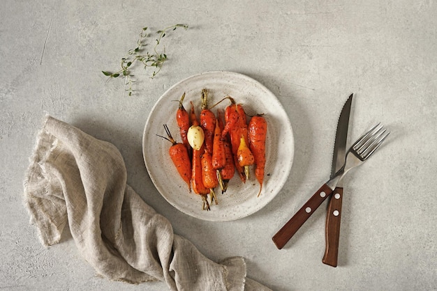 Fried carrots with herbs served on the plate on light table vegan food top view