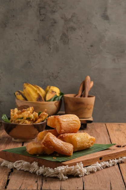 Fried cassava is served on a cutting board with a banana leaf
base. arranged in such a way with a classic kitchen table
theme