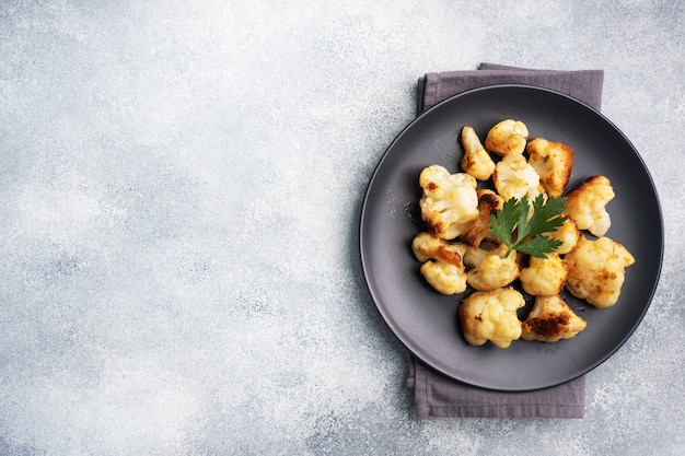 Fried cauliflower florets in batter on a black plate