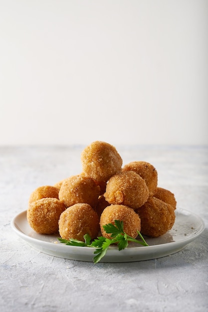 Fried cheese balls, appetizer with herbs and sauces in a plate on a gray table