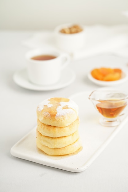 Fried cheese cakes, sweet cheese pancakes on white plate on white background, vertical. 