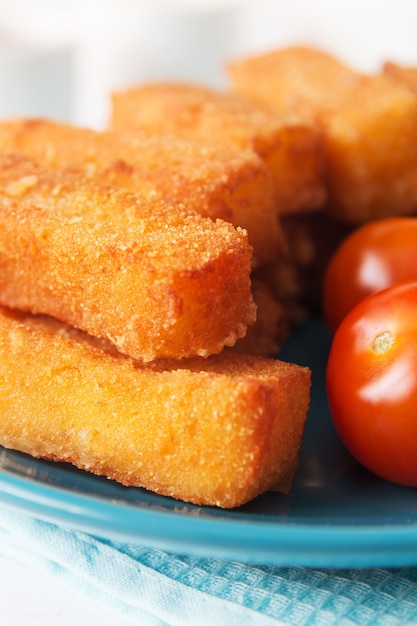 Fried cheese sticks with tomatoes on a blue plate