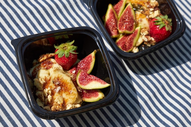 Photo fried cheese with nuts strawberries and fig slices in a plastic plate