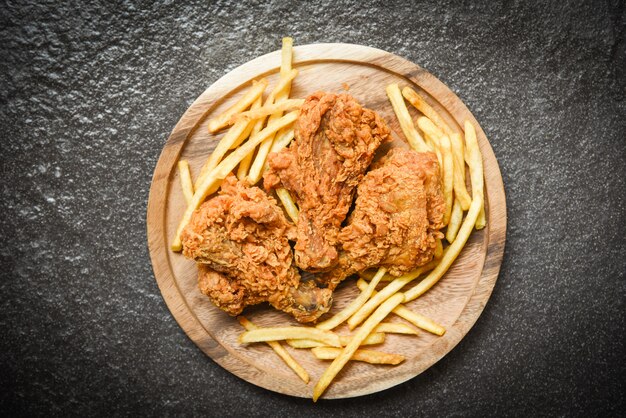 Fried chicken crispy on wooden tray with french fries on dark 