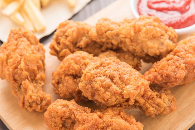 Fried chicken drumstick and french fries on wooden table