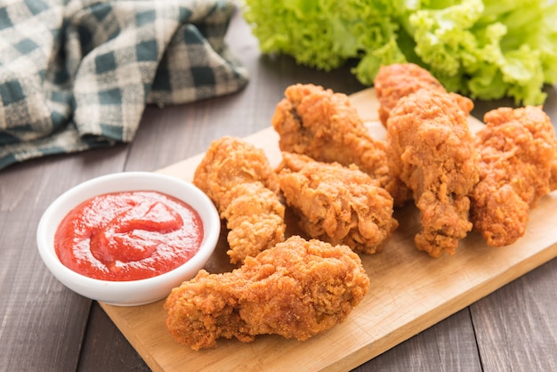 Fried chicken drumstick and vegetables on wooden table