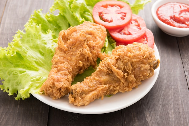 Fried chicken drumstick with tomato on wooden background