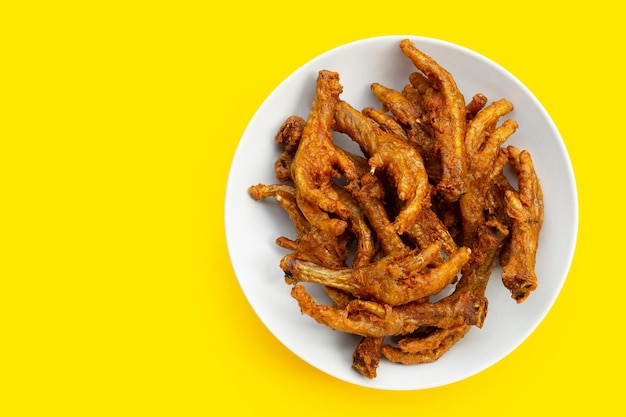 Foto piedini di pollo fritti in piatto bianco su sfondo giallo