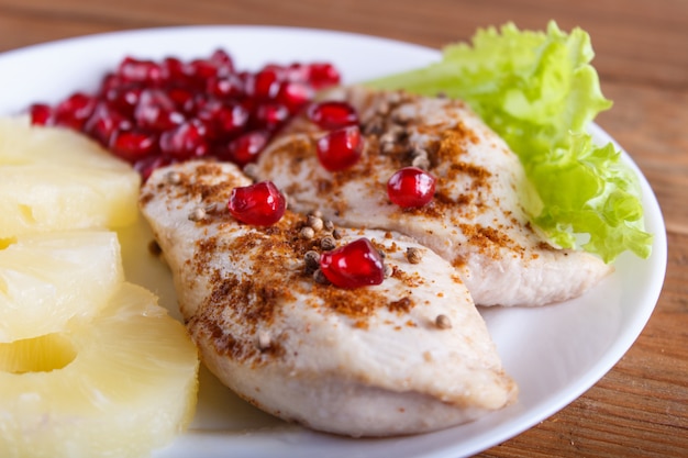 Fried chicken fillets with lettuce, pineapple and pomegranate seeds 